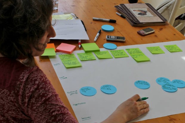 Picture shows a researcher helping to fill out a user research exercise at a kitchen table