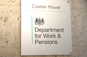 A sign mounted onto the wall of a stone building reads 'Caxton House', 'Department of Work and Pensions'