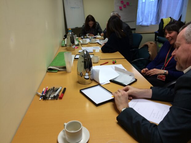 People are sitting at a table covered in paper and pens, creating imaginary 'ideal policy tools'.