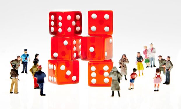 Small figurines of people standing around two towers made up of red dice