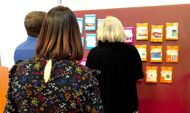 Three attendees at a recent co-design event looking at some evidence cards that gave examples from other countries