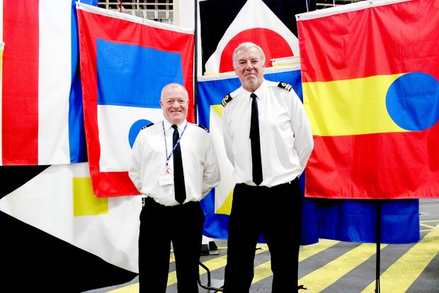 This is an image of marine vexillologists, flag experts, in front of the speculative flag installation by Policy Lab onboard the RFA Lyme Bay ship at London International Shipping Week 2019.