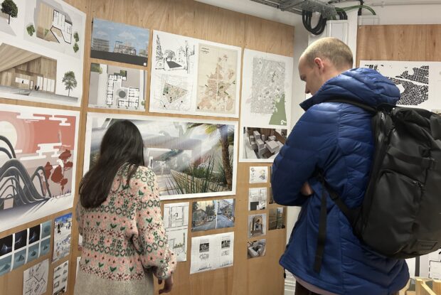 A woman and a man looking at a board with a display of posters